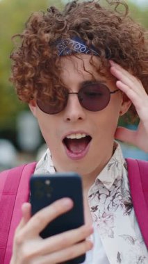 Mobil akıllı telefonu kullanan genç adam iyi haber kazandı, piyango büyük ikramiyesi kazandı, açık havada dağıttı. Vay be duygu. Şehir caddesinde duran mutlu turist. Kasaba yaşam tarzları