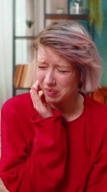 Evde diş ağrısı çeken bir kadın. Yüzünde rahatsız edici bir ifadeyle yanak tutuyor. Beyaz kız açıkça diş rahatsızlığı gösteriyor, diş ağrısı çekiyor, koltukta endişeli bir şekilde oturuyor..