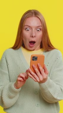 Mutlu Kafkasyalı genç kız akıllı telefon daktilo kullanıyor bağırarak evet de büyük ikramiye kazan iyi haber piyango hedefi başarıyı kutla, sarı ile oyun kazan