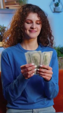 Başarılı, kıvırcık saçlı zengin kadın evdeki kanepede otururken dolar banknotları sayıyor. Gülümseyen kız bütçeyi hesaplıyor, birikimleri, kazançları, apartman dairesinde tatil planları yapıyor..