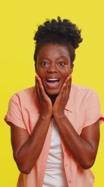 Aman Tanrım, vay canına. Heyecanlı afro-amerikan kadın kameraya büyük gözlerle bakıyor başarıyı kutlayan ani zaferin şokuyla iyi haberler. Sarı arka planda sürpriz bir kız.