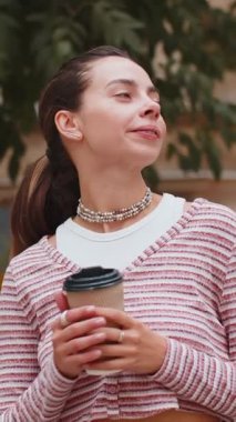 Mutlu genç bayan sabah kahvesinin tadını çıkarıyor sıcak bir içecek ve dışarıda gülümsüyor. Dinleniyorum, ara veriyorum. Diş teli takmış bir kız şehir merkezinin caddesinde yürüyor, kahve içiyor.