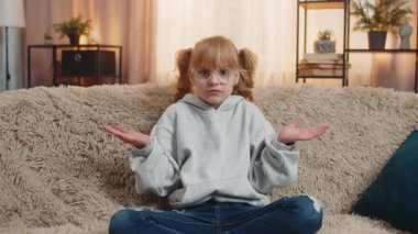 Ne diyecegimi bilmiyorum. Genç bir kız omuzlarını silkip evde şaşkın ve belirsiz bir ifade takınıyor. Kafkasyalı çocuk kanepede oturuyor, kafa karışıklığı ve belirsizlik gösteriyor.