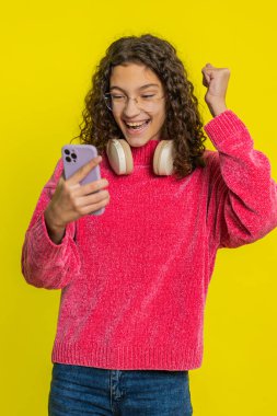 Mutlu beyaz kız çocuğu akıllı telefon daktiloyla yazı yazarak 