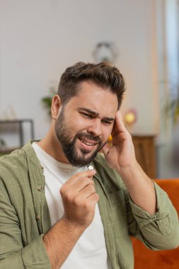 Baş ağrısı çeken bir adam oturma odasında ilaç, sağlık ve tedavi görüyor. Erkek hasta ilaç, anksiyete ya da su, ilaç ya da hastalığın tedavisi.