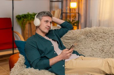 Evdeki genç adam kanepeye uzanıyor gözleri kapalı ve kulaklıkları açık, sesli kitap dinliyor. Kafkasyalı adam sakin ve huzurlu görünüyor, sakin uzayın rahatlığından ve hayal gücünden zevk alıyor.