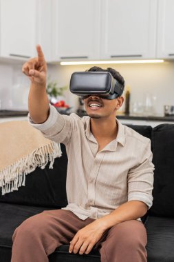 Evde oturan Hintli adam VR kulaklık takıyor. Vay be, film izliyor ve sanal sinemayı ilgiyle keşfediyor. Kanepedeki Arap adam internet içeriği hakkında konuşuyor. Kısa kelimeler söylüyor. Kafa sallıyor ve sakin hareket ediyor.