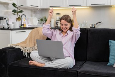 Evde genç bir kadın dizüstü bilgisayarı açar harika haberler görür ve 