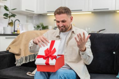 Evdeki genç adam hediye kutusunu açtı. Kapağı kaldırdı. İstenilen nesneyi buldu ve büyük bir sürprizle dondu. Kanepede oturan beyaz bir adam gülümsüyor. Bir an için kutuyu tutuyor ve büyük bir sevinç şoku yaşıyor..
