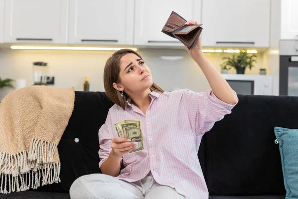 Evdeki genç kadın cüzdanın içine baktığında az miktarda nakit para görüyor ve yoksulluk ve borçtan rahatsız oluyor. Kanepede oturan beyaz kız gol atmayı planlıyor. Maliyetleri ve bütçeyi düşürüyor ve endişeli ruh hali ve stresi gösteriyor.