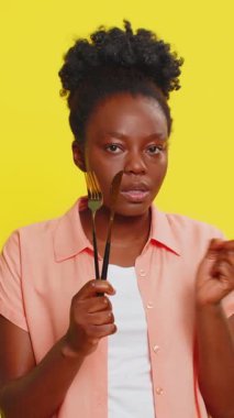 Afro-Amerikalı kadın, elinde çatal ve bıçakla elini sallayarak yiyeceği reddettiğini gösteriyor. Sarı arka planda siyah bir kız. Beslenme ve beslenme kontrolünü sürdürme kararlılığı