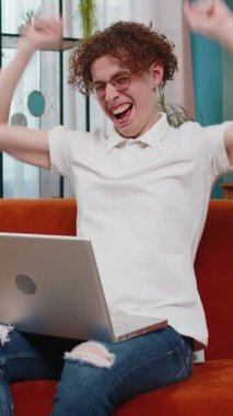 Kafkasyalı bir adamın üzerine para yağmuru yağıyor laptopta çalışıyor başarıyı kutluyor, kazanıyor, gol başarısı, iyi haber piyango ikramiyesi. Kariyer büyür. Oturma odasındaki kanepede oturan genç adam.