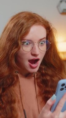 Kafkasyalı, saçları rüzgarla taranmış, akıllı telefon kullanan, iyi haber mesajı alan, piyango ikramiyesini kazanmasını kutlayan, sürpriz bir beyaz kadın. Yaşam Tarzları.