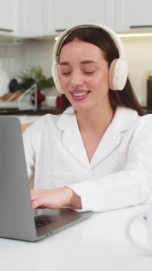 Evde kulaklık takan genç bir kadın dizüstü bilgisayarla gülümseyip ritme göre başını sallıyor ve müşteriye e-posta yazıyor. Kanepede oturan beyaz bir kız müzik dinliyor. Tuşlara basıyor. Düzenli bir ritmi var..