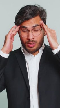 Memnun olmayan Hintli iş adamı baş ağrısı problemini tedavi etmek için tapınakları ovuyor, tansiyon, migren, stres, ekşitme, acı içinde kıvranıyor, yüksek tansiyon sadece gri arka planda izole.