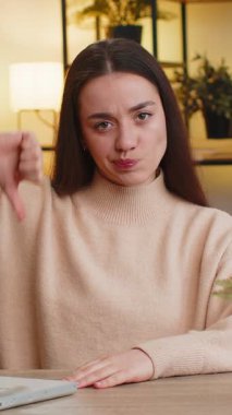 Hoşlanmamak. Mutsuz, Kafkasyalı kadın işaret dilini gösteriyor, hoşnutsuzluğunu dile getiriyor, evde çalışmaktan memnun değil. Masadaki odada hoşnutsuz genç kız.
