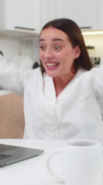 Evdeki genç kadın indirim görüyor gülümseme atlayışları yapıyor ve tanıtım kodlarını sırayla kutluyor. Kanepede oturan beyaz kız dizüstü bilgisayarda çalışıyor. Ödemeler internet üzerinden yapılıyor. Alkışlar sevindirici..