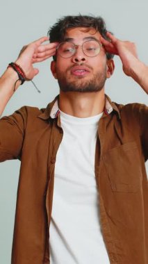 Memnun olmayan Hintli Hintli adam baş ağrısı problemini tedavi etmek için tapınakları ovuyor, tansiyon, migren, stres, ekşitme, acı içinde kıvranıyor, yüksek tansiyon tek başına gri arka planda izole edilmiş.