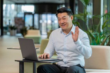 Modern ofis lobisinde dizüstü bilgisayarda çalışan kendine güvenen bir iş adamı çalışanla online iletişim videosu konuşması yapıyor, patron. Tişört destek servisinde yönetici bilgisayarın webcam 'ine bakıyor