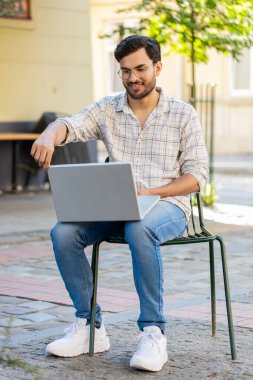 Sandalyede oturan Hintli serbest yazar dizüstü bilgisayarını açar teneffüste internet üzerinden iş arama web sitesinde sohbet etmeye başlar. Genç adam netbook ekranına bakıyor, mesajlar gönderiyor, film izliyor..