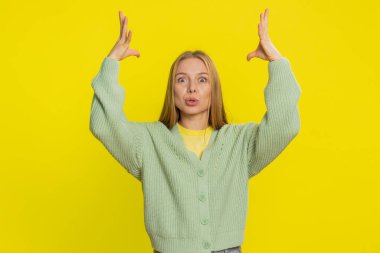 Şaşırmış, heyecanlı, orta yaşlı, beyaz, sarışın kadın kafasına dokunuyor ve kafa patlaması gösteriyor. Endişeli ve şok olmuş görünüyor, profesyonel olarak tükenmiş. Sarı arka planda izole edilmiş genç bir kız.