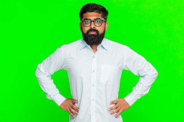 Hintli bir adam çenesini sıkar ve ellerini kalçasına koyar. Gergin duruşta duygusal stres yaratır. Arabistanlı adam yeşil krom anahtar arka planda izole edilmiş sinirsel çöküntü gösteriyor