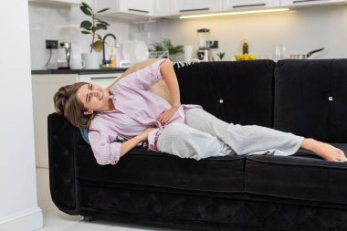 Regl sancısı çeken hasta bir genç kadın, evinde ağrılı bir mide ağrısı. Kanepede karnını tutan bir kız, karın ağrısı ya da regl ağrısı çekiyor. Karın ağrısı, mide iltihabı, ishal, hazımsızlık.