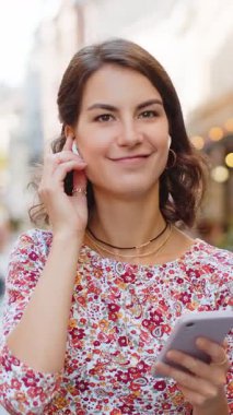 Neşeli, aşırı neşeli, kablosuz kulaklık takan, dans eden, açık havada dans eden, Disko Rock 'n Roll müziği dinleyen beyaz bir kadın. Şehir caddesinde yürüyen kız