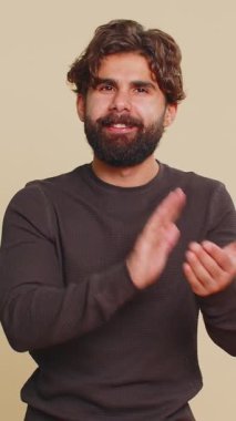 İyi iş çıkardın. Lübnanlı genç adam başparmağını sallıyor ve onaylıyor, el çırpıyor, başarılı bir iş çıkarıyor, tatmin oluyor, kutluyor. Hintli İspanyol adam bej renkli stüdyoda izole edilmiş..