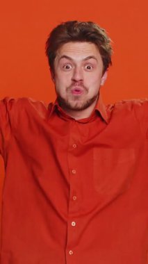 Kafasına dokunup patlama gösteren, endişeli ve şok olmuş görünen, başarıyı kutlayan, iyi fikir, iyi cevap veren, heyecanlı beyaz adam. Turuncu arka planda izole edilmiş yakışıklı bir adam.