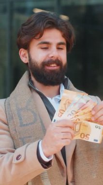 Şehir merkezindeki sokakta elinde euro banknotları tutan başarılı genç Hintli adam. Mutlu yetişkin Hindu adam çevrimiçi piyango oyunu kazanıyor. Bütçeyi hesaplamak için nakit kredi teklif ediyor.