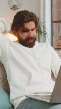 Evdeki kanepede oturan üzgün genç Hintli adam dizüstü bilgisayar kullanıyor ve stres altında. Sakallı adam kayıplara tepki veriyor. Oturma odasındaki internet sitesinde kötü haberler. Bilgisayar virüsü.