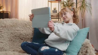 Genç kız evde renkli bir resim çiziyor, tablet üzerinde dikkatle taşınan bir stil. Kanepedeki sarışın çocuk, dijital sanat eserlerine gururla gülümseyen, son yaratılışa hayran..