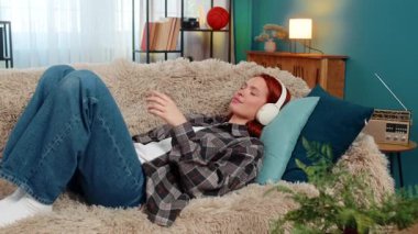 Evde gözleri kapalı sesli kitap dinleyen genç bir kadın zihninde huzurlu bir şekilde hikaye sahneleri canlandırıyor. Kafkasyalı kızıl saçlı kız koltukta, sakin anın tadını çıkarıyor, ses, ses ve hayal gücüne odaklanmış.