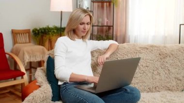 Orta yaşlı bir kadın dizüstü bilgisayarını kapatıyor ve kızgın bir şekilde elini sallayarak hayal kırıklığına uğruyor. Yetişkin kadın uzun ve stresli bir çalışma seansından sonra duygusal çöküntü ve tatminsizlik yaşıyor.