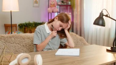 Masasında oturan çocuk ödevlerini yapıyor. Düşünceli bir şekilde defter açık, sorunlara çözüm arıyor. Okul çocuğu mutlu bir şekilde doğru cevabı buluyor, heyecanlı bir şekilde gülümsüyor, neşeli bir şekilde anlıyor.