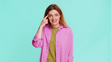 Orta yaşlı bir kadın şakacı bir yüz ifadesiyle şakacı bir ifadeyle şakacı bir şekilde birine deli diyor. Mavi arka planda izole edilmiş bir kız klasik jest ve duyguyu gösterir.