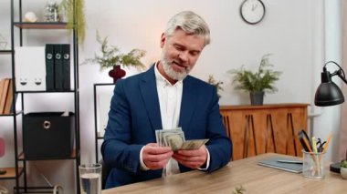 Merkez ofisteki orta yaşlı işadamı, yeni maaş geliri sayarak kazandığını hissederek dolarları sallıyor. Masadaki serbest çalışan adam büyük bir zaferin tadını çıkaran ikramiye planlama yatırımları yapıyor..