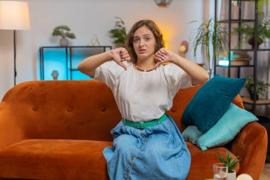 Hoşlanmamak. Mutsuz bir kadın portresi işaret levhası gösteriyor. Memnuniyetsizliğini dile getiriyor. Evde yapılan kötü işler hoşnutsuz. Oturma odasında kanepede hoşnutsuz bir kız. Yaşam Tarzları