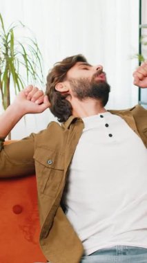 Orta Doğu 'lu yorgun bir adam yatakta uzanıyor ve evde dinleniyor. Kaygısız genç sakallı adam uyukluyor, rahat koltukta yastıklarla uyuyakalıyor. Kapalı gözler, tek başına gündüz uykusunun tadını çıkar.