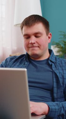 Kanepede oturup dizüstü bilgisayarını kapatan ve oturma odasındaki işini bitirdikten sonra dinlenen mutlu beyaz adam. Genç serbest çalışan biri evde uzaktan kumanda işinde çalışıyor. Netbook 'ta e-öğrenme, internette gezinme.