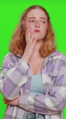 Ne diyecegimi bilmiyorum. Kafası karışmış bir kadın belirsiz bir soru hakkında utanır, şüpheleri vardır, cevabı yoktur, fikri yoktur, bilgisizdir, belirsizdir. Kızıl saçlı kız yeşil krom anahtar arka planında izole edilmiş.