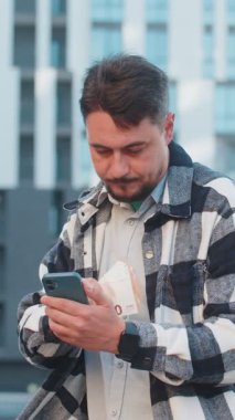 Zengin, olgun, beyaz iş adamı turist akıllı telefon kullanıyor ve şehir merkezinde nakit para sayıyor. Başarılı iş kariyeri, piyango kazananı, büyük gelir, zenginlik.