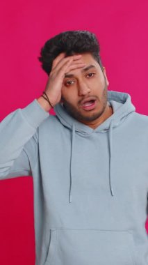 Üzgün genç Hintli adam umutsuzluk yalnızlık, sinir bozukluğu, kaybediyor piyango sonuçları, kötü talih, şanssız haberler karşısında şaşırıyor. Çekici Hindu adam pembe arka planda izole edilmiş.