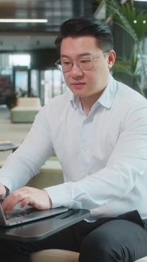 Gibi. Bilgisayarda çalışan mutlu genç işadamı kameraya bakıp olumlu bir işaret veriyor. Modern ofis lobisinde oturan olumlu bir geri bildirim gibi. İş insanları