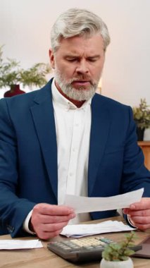 Merkez ofisteki orta yaşlı işadamı bugün hesap makinesi tarama makbuzlarını kullanarak bütçeyi gözden geçiriyor. Masa girişindeki serbest çalışan adam, para akışı bakiyesi tahmini giderlerini ayarlıyor.