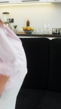 Evdeki genç kadın derin bir nefes alıp rahatlıyor ve iyileşme ve rahatlama düşüncelerini yavaşlatıyor. Kanepede oturan beyaz kız arkasını yaslıyor boyun ve omuz kaslarını esnetiyor ve sakin bir duraksamanın keyfini çıkarıyor..