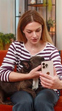 Evde Fransız bulldog 'u olan orta yaşlı bir kadın akıllı telefon programlarındaki veterinerlere tavsiye için video çağrısı yapıyor. Kız, köpekle kanepede oturur, aşıyla ilgili tavsiyeler dinler ya da sakin bir ruh hali desteği ister..