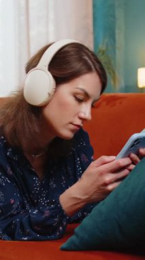 Kablosuz kulaklıklı mutlu kadının portresi evde koltuğa uzanmış en sevilen disko müziği dinlerken dinleniyor. İnsanlar hafta sonu boş zaman aktiviteleri.