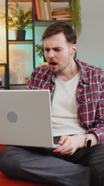 Evdeki kanepede oturup dizüstü bilgisayar kullanan sinirli ve stresli genç bir adam. Ekose gömlekli beyaz adam kötü piyango oyununu kaybetmeye tepki veriyor. Oturma odasında netbook 'ta haberler var.